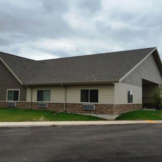 A residential house with a sloped roof and surrounding lawn.