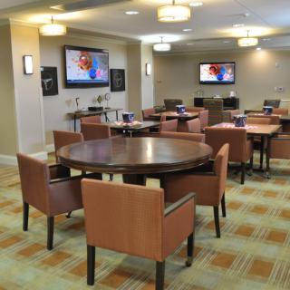A modern conference room with round tables, comfortable chairs, and wall-mounted televisions.