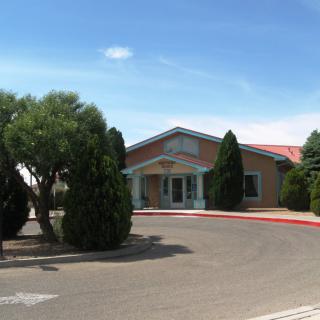 A building with a red roof surrounded by trees on a sunny day.