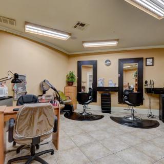 An interior view of a hair salon featuring chairs, mirrors, and workstations.
