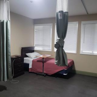 A hospital room featuring a single bed with privacy curtains.