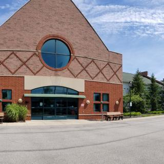 A brick church with a circular window and an arched entrance.