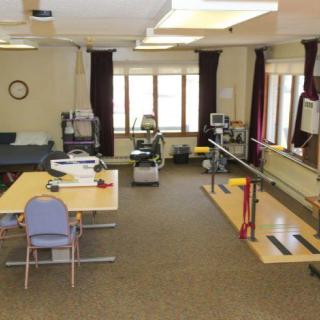 A physical therapy clinic equipped with exercise machines and parallel bars.