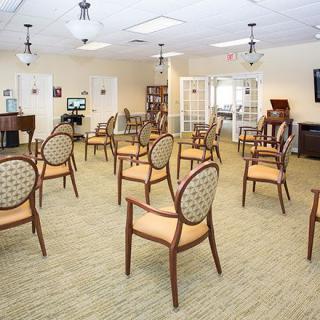An empty conference room with rows of chairs arranged neatly on a carpeted floor.