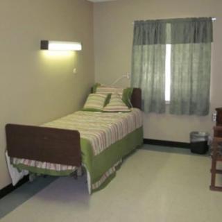 A minimalist hospital room with a single bed and green accents.