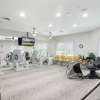 A well-lit gym with various fitness equipment including treadmills and stationary bikes.