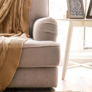 A cozy armchair draped with a blanket next to a side table in a warmly lit living room.