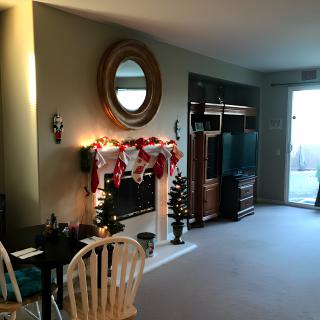 A cozy living room adorned with Christmas decorations, featuring a fireplace and mirror.