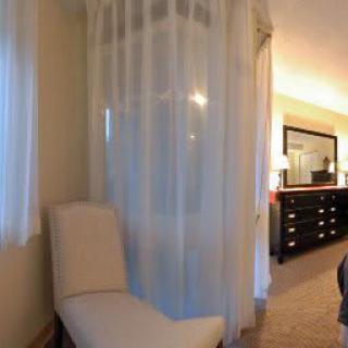 Cozy bedroom corner with a beige chair and a large dresser.