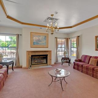 A cozy living room with a fireplace, sofas, and large windows.