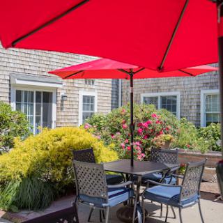 A peaceful outdoor patio setup with red umbrellas, perfect for enjoying a sunny day in the garden.