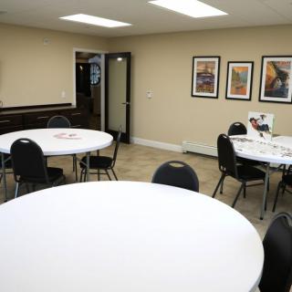 An empty conference room with round tables, chairs, and artwork on the walls.