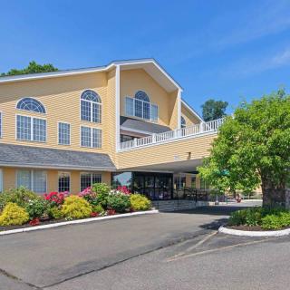 A modern hotel building with attractive landscaping and a spacious parking area on a clear day.
