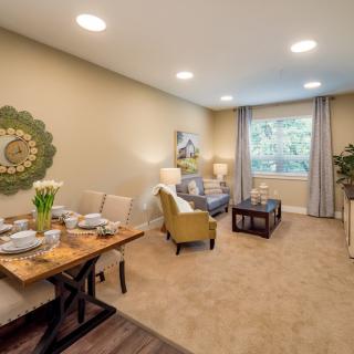 A cozy living and dining area with comfortable seating, stylish decor, and a view through a large window.