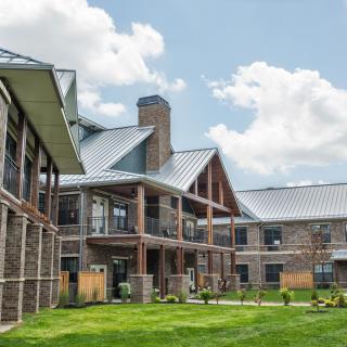 A modern residential building with a well-maintained lawn under a blue sky with clouds.