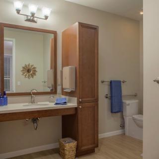 A modern bathroom interior featuring a wooden finish with a sink, mirror, and neatly arranged towels.