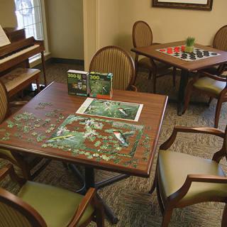 A cozy indoor setting with tables and chairs, featuring a partially completed jigsaw puzzle and board games.