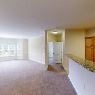 Spacious living room with carpet flooring and ample natural light.