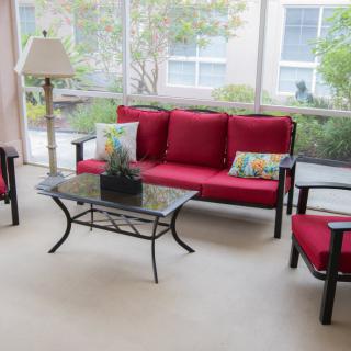 A cozy living room with red-cushioned seating and a glass coffee table.
