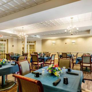 A spacious dining room with elegantly set tables and chandeliers.