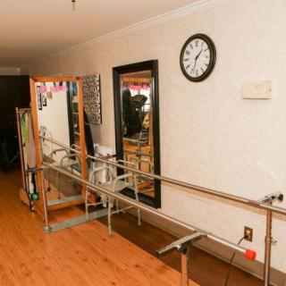 A therapy room equipped with parallel bars and a mirror for rehabilitation exercises.