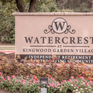 Entrance sign for Watercrest at Kingwood Garden Village, an independent retirement living community, with well-maintained landscaping and flowers.
