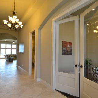 A bright and modern hallway featuring a chandelier and glass doors in a residential setting.