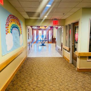 A brightly lit hallway adorned with a colorful rainbow mural, leading to a welcoming entrance.