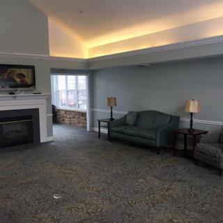 A cozy living room with a fireplace, surrounded by sofas and lamps.