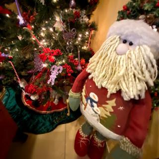 A festive Santa Claus decoration stands beside a beautifully adorned Christmas tree.