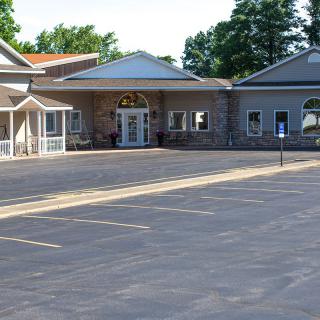 A single-story building with a parking lot in front, surrounded by trees.