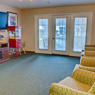 A cozy lounge area with upholstered chairs, a television, and a popcorn machine.