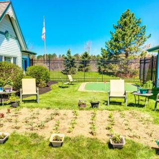A sunny backyard with lawn chairs and a small garden plot.