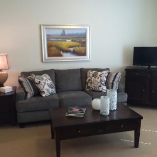 A cozy living room with a sofa, coffee table, and artwork on the wall.
