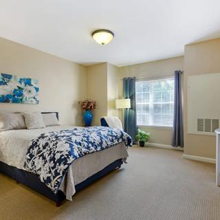 A cozy bedroom interior with a large bed, a window with curtains, and decorative elements.