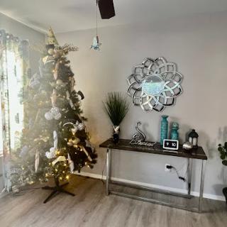 A beautifully decorated living room featuring a Christmas tree, stylish decor, and a modern mirror.