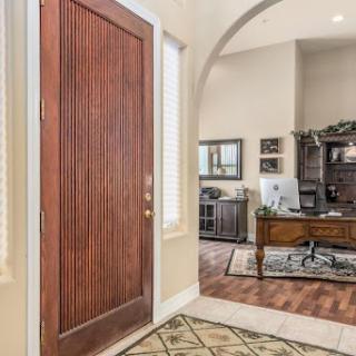 A welcoming entrance featuring a wooden front door and glimpse of a cozy home office.