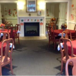 A cozy dining room with red tablecloths and a central fireplace.