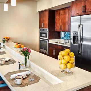 A modern kitchen with a sleek countertop featuring stainless steel appliances and decorative elements like lemons and flowers.