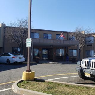 A view of a hotel building in a parking lot on a sunny day.