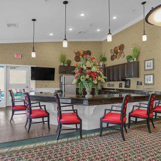 A modern kitchen and seating area featuring pendant lighting and vibrant red chairs.