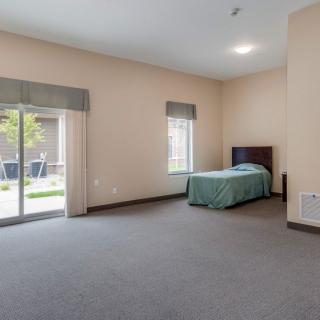 A spacious bedroom with a single bed and large windows allowing natural light.