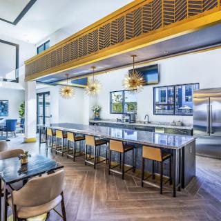 A sleek and modern kitchen featuring a bar area with stylish seating and elegant lighting.