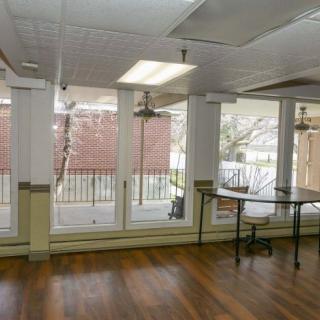 A bright room with large windows, wooden floors, and ceiling fans.