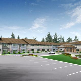A modern building with a parking lot and landscaped surroundings under a clear sky.