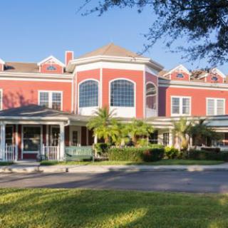 A large, elegant red building with a porch and surrounding greenery.