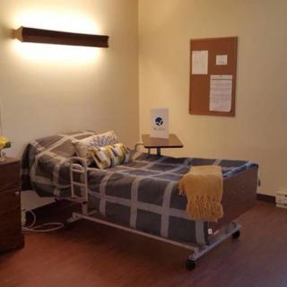 A simple hospital room with a single bed and minimalist decor.