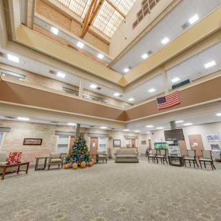 A spacious atrium with multiple levels, featuring comfortable seating, decorative elements, and a skylight overhead.