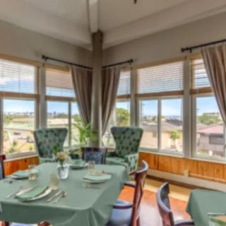 A sunlit dining room with elegantly set tables and large windows offering a scenic view.