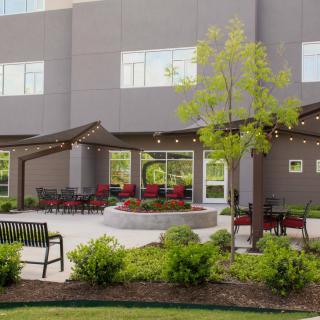 A modern patio featuring comfortable seating, pergolas, and well-maintained landscaping outside a building.